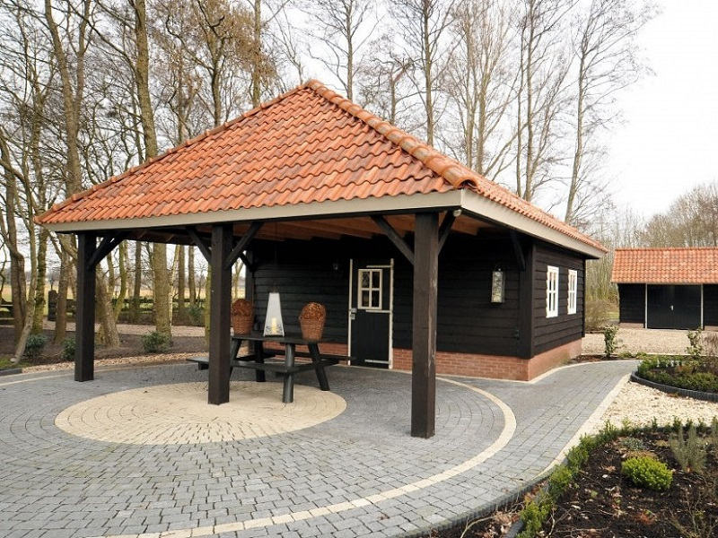 Houten mantelzorgwoning in houtskeletbouw met zwarte gevel, pannendak en overkapping