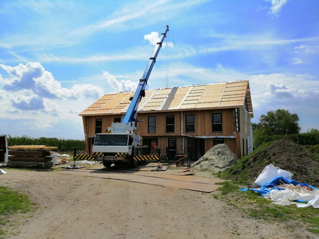 Houtskeletbouw in aanbouw: kraan plaatst prefab dakelementen op een verblijf in Vrouwenpolder