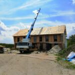 Houtskeletbouw in aanbouw: kraan plaatst prefab dakelementen op een verblijf in Vrouwenpolder