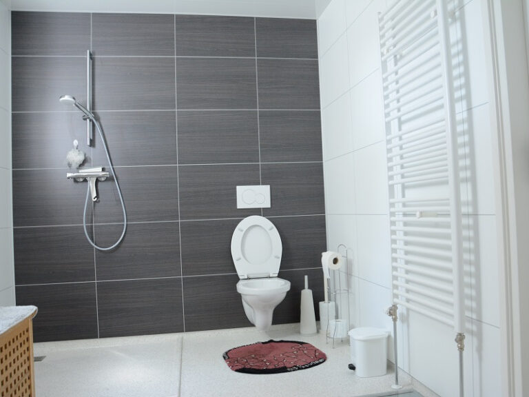 Toilet en douche in een compacte badkamer van een houten recreatiewoning
