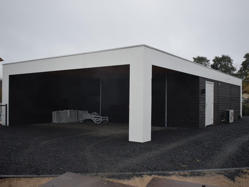 Houten carport met staanders naast een woning met zwarte gevel