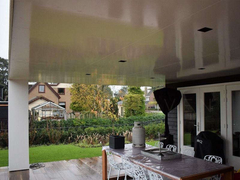 Overkapping aan de achtergevel met inbouwspots in het plafond boven de buitentafel