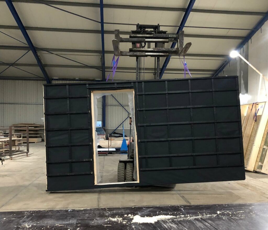 Afgewerkt prefab wandelement met zwarte dampopen folie aan de kraan in de fabriek